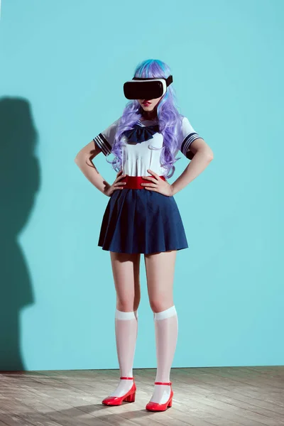 Full length view of girl in bright wig using virtual reality headset and standing with hands on waist on blue — Stock Photo