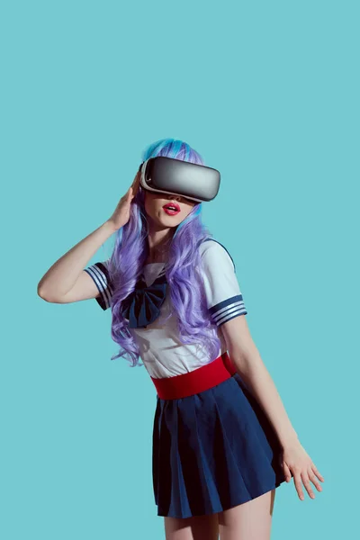 Chica con estilo en peluca violeta usando auriculares de realidad virtual aislados en azul - foto de stock