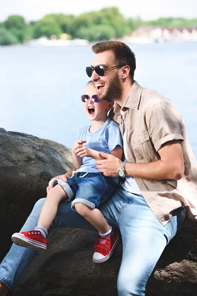 Laughing father and son looking away at park — Stock Photo