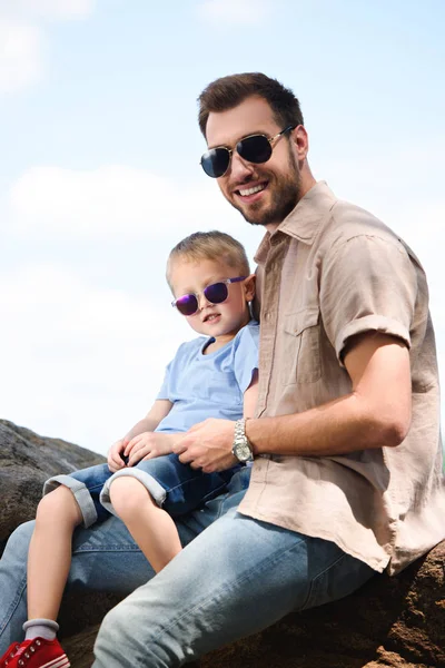 Щасливий батько і син в сонцезахисних окулярах дивиться на камеру в парку — стокове фото