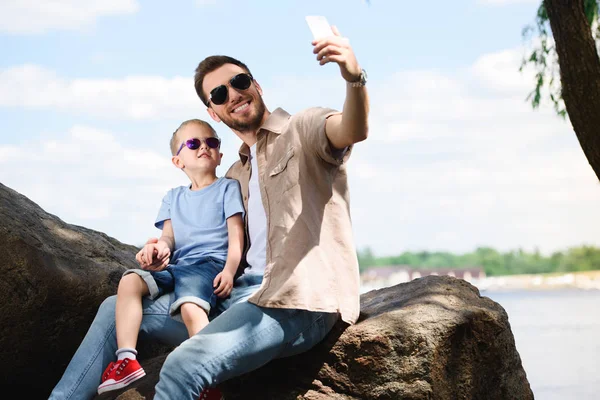 Батько і син беруть селфі зі смартфоном у парку — стокове фото