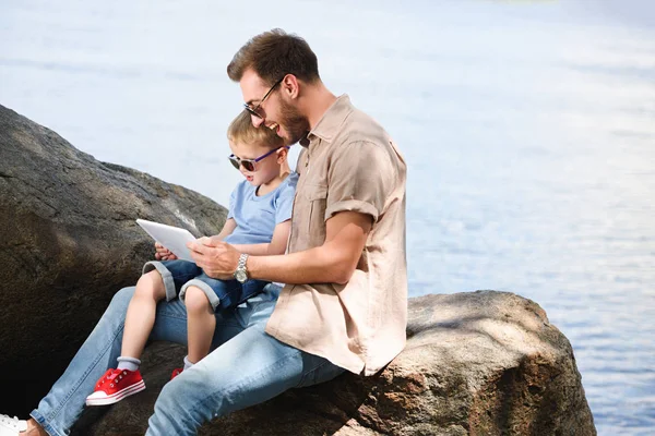 Père et fils utilisant tablette près du lac au parc — Photo de stock
