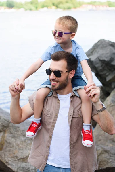 Heureux papa tenant fils sur les épaules et ils regardent loin au parc — Photo de stock