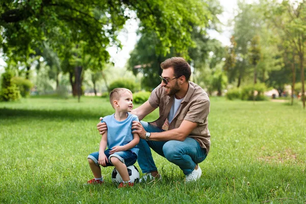 Father and son looking at each other after playing football at park — Stock Photo