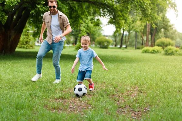 Padre e hijo jugando al fútbol en el parque - foto de stock