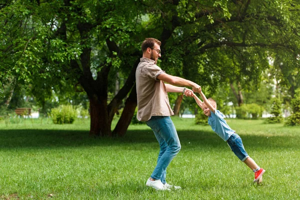 Father spinning around son and they having fun at park — Stock Photo