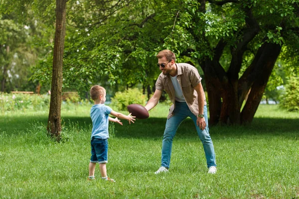 Feliz pai e filho jogando futebol americano no parque — Fotografia de Stock