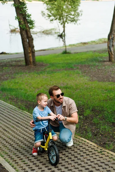 Vater und Sohn mit kleinem Fahrrad schauen beim Parken weg — Stockfoto