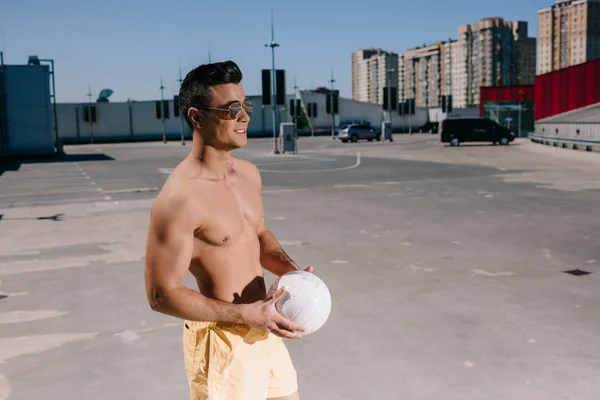 Щасливий без сорочки чоловік тримає волейбол м'яч на парковці — стокове фото