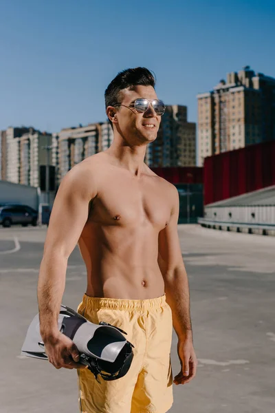 Smiling young shirtless man with flippers on parking — Stock Photo