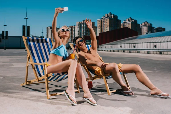 Jovem casal relaxante em espreguiçadeiras com coquetéis e tirar selfie no estacionamento — Fotografia de Stock