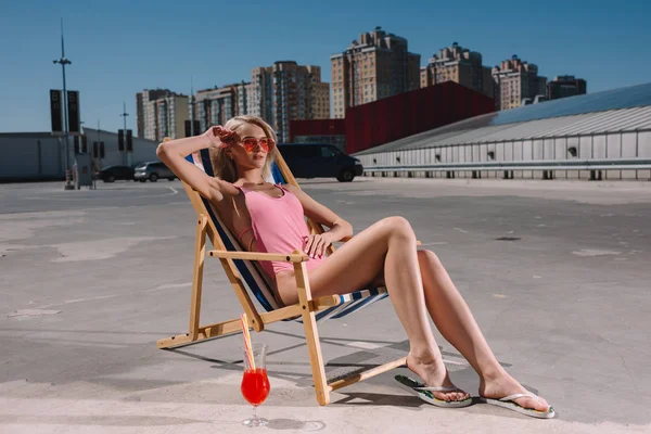 Attractive young woman relaxing in sun lounger on parking — Stock Photo