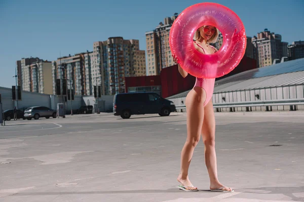 Attrayant jeune femme en maillot de bain avec anneau gonflable sur le parking — Photo de stock