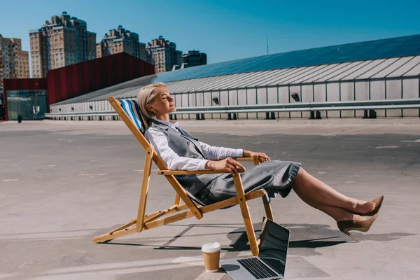 Glückliche junge Geschäftsfrau in formeller Kleidung entspannt in der Sonnenliege auf dem Parkplatz — Stockfoto
