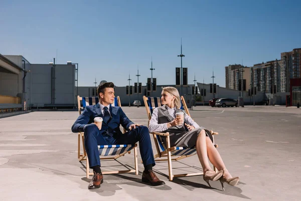 Jóvenes de negocios relajarse en tumbonas con café para ir en el aparcamiento - foto de stock