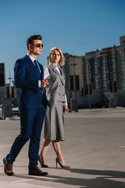 Young stylish business people with car alarm remote walking on parking — Stock Photo