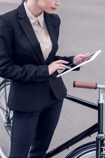 Cropped shot of businesswoman using digital tablet while standing near retro bicycle on street — Stock Photo
