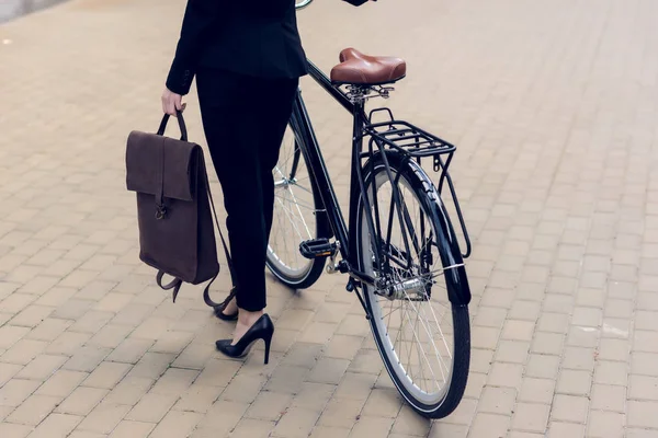 Partial view of businesswoman with briefcase and retro bicycle on street — Stock Photo