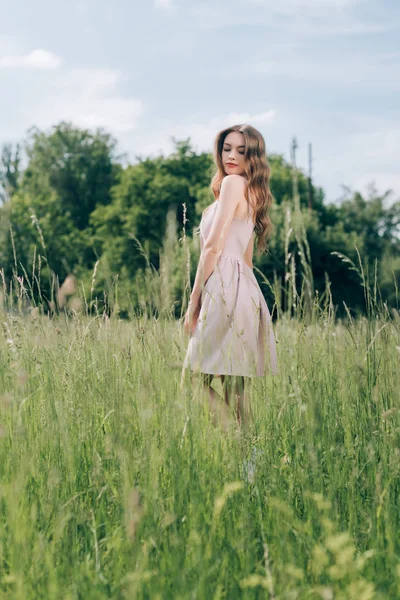Young pretty woman in stylish dress standing in meadow alone — Stock Photo