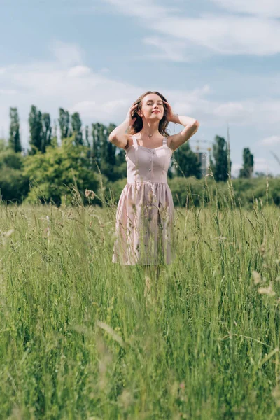 Porträt einer jungen schönen Frau in stylischem Kleid, die allein auf der Wiese steht — Stockfoto