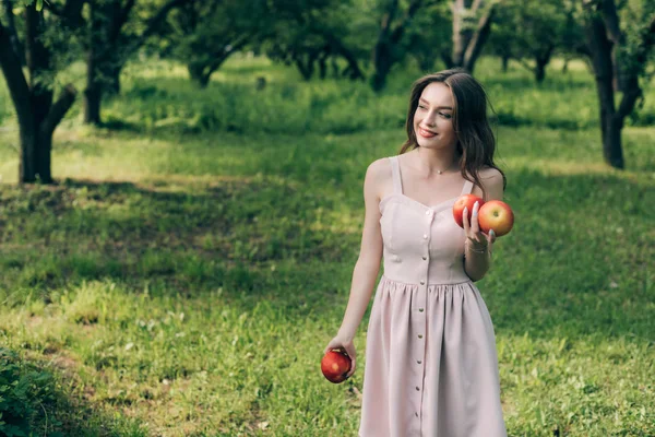 Portrait de jeune femme souriante en robe aux pommes mûres à la campagne — Photo de stock