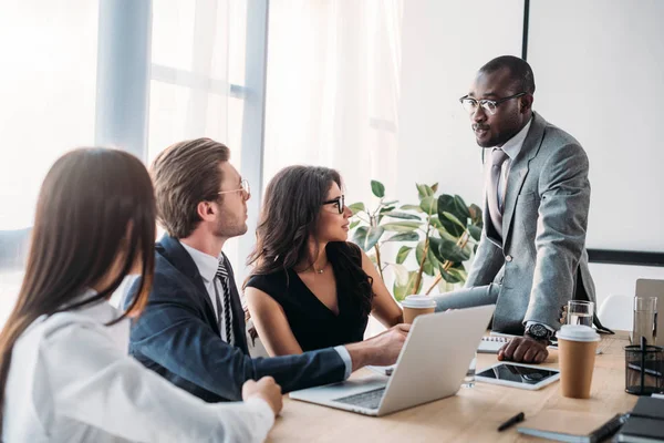 Partial view of multiracial group of business coworkers in formal wear discussing new business plan in office — Stock Photo