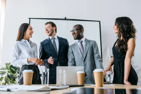 Усміхнені мультикультурні бізнесмени мають ділову зустріч в офісі — стокове фото