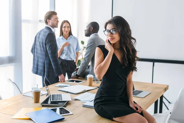 Selektiver Fokus der afrikanisch-amerikanischen Geschäftsfrau im Gespräch über Smartphone und multikulturelle Kollegen im Büro — Stockfoto