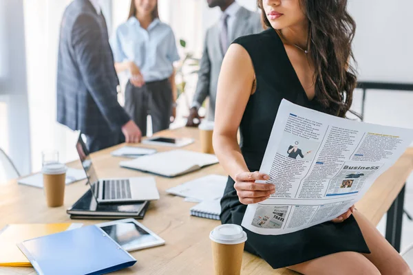 Partial view of african american businesswoman with newspaper and multicultural colleagues in office — Stock Photo