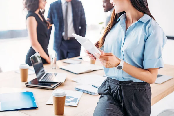 Visión parcial de la mujer de negocios con tableta y colegas detrás en el cargo — Stock Photo