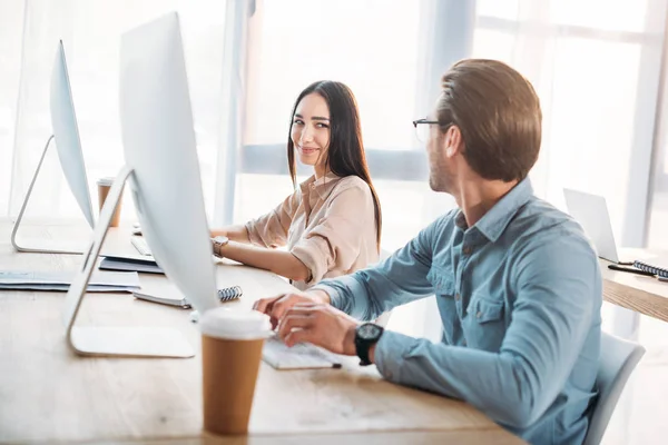 Colleghi di lavoro interrazziali che si guardano mentre lavorano sul posto di lavoro in ufficio — Foto stock