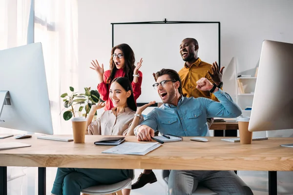 Glückliches multiethnisches Business-Team, das gemeinsam im Büro an einem Projekt arbeitet — Stockfoto