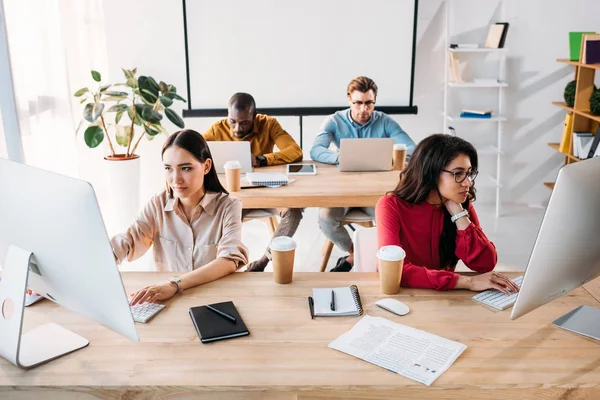 Jóvenes empresarios interracial enfocados que trabajan en la oficina - foto de stock