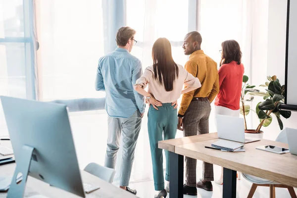 Vista posteriore di colleghi d'affari multietnici che guardano fuori dalla finestra in ufficio — Foto stock