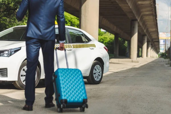 Schnappschuss von stilvollem Geschäftsmann mit Koffer, der neben Taxi steht — Stockfoto