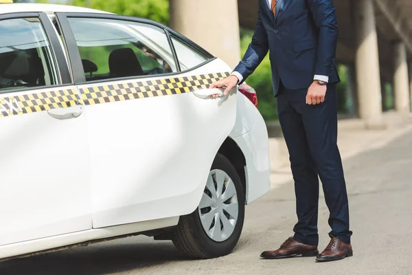 Cropped shot of young man in suit opening door of taxi cab — Stock Photo