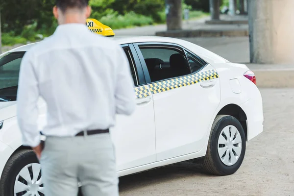 Vue arrière du jeune chauffeur qui va en taxi dans la rue — Photo de stock