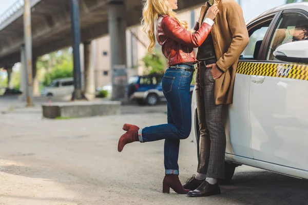 Plan recadré de jeune couple élégant étreignant tout en se tenant ensemble près de taxi — Photo de stock