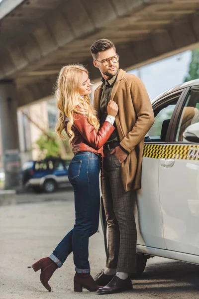 Happy stylish young couple standing together near taxi cab — Stock Photo