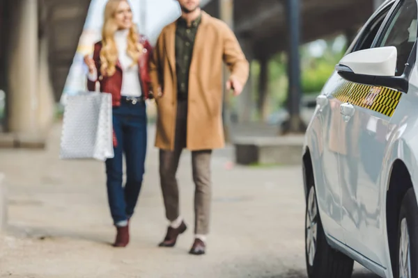 Foyer sélectif de jeune couple avec sacs à provisions allant à la cabine de taxi — Photo de stock