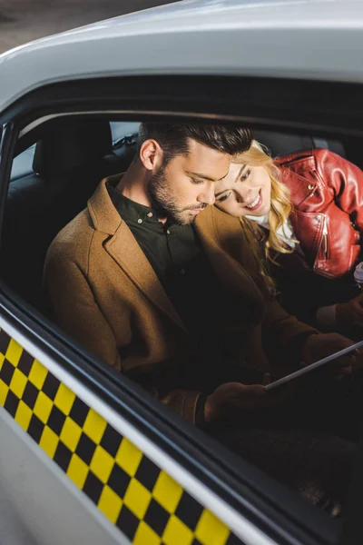 Stilvolles junges Paar nutzt digitales Tablet im Taxi — Stockfoto