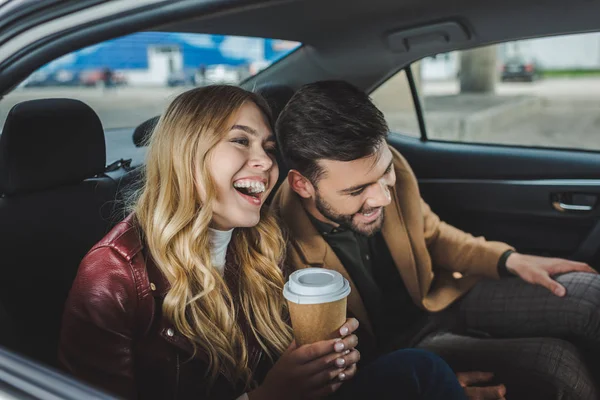 Feliz jovem casal rindo enquanto sentados juntos em táxi — Fotografia de Stock