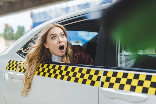 Messa a fuoco selettiva della ragazza scioccata guardando lontano attraverso il finestrino del taxi — Foto stock