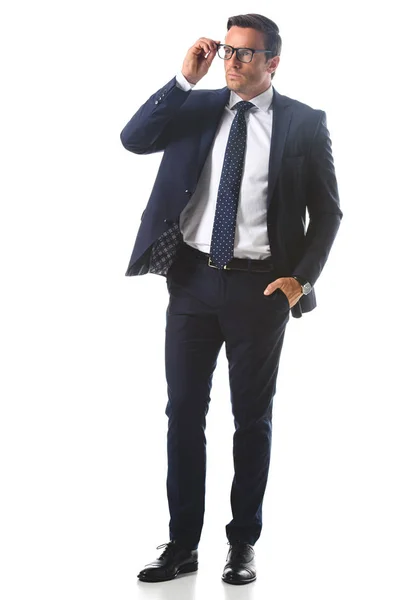 Серйозний бізнесмен з рукою в кишені, регулюючи окуляри ізольовані на білому тлі — стокове фото