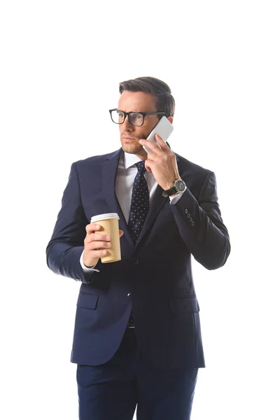 Seriöser Geschäftsmann mit Brille, der auf dem Smartphone spricht und eine Papptasse Kaffee auf weißem Hintergrund hält — Stockfoto