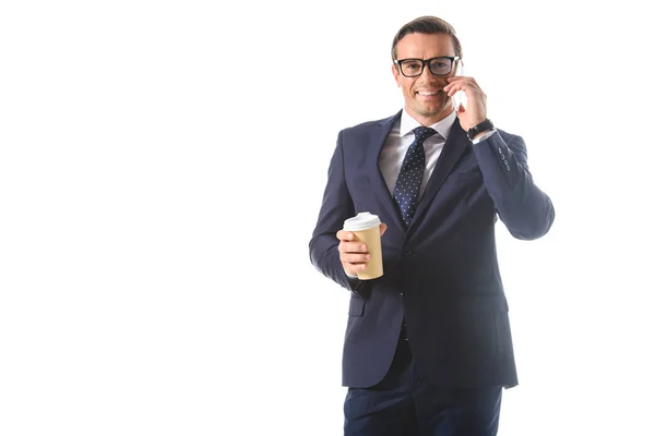 Felice uomo d'affari in occhiali parlando su smartphone e tenendo tazza di carta di caffè isolato su sfondo bianco — Foto stock