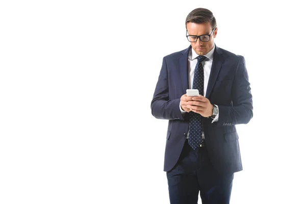 Serious businessman in eyeglasses checking smartphone isolated on white background — Stock Photo
