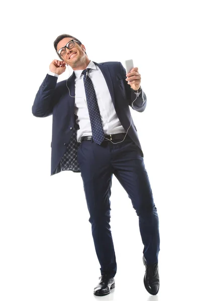 Relajado hombre de negocios en gafas de vista escuchando música en auriculares con teléfono inteligente aislado sobre fondo blanco - foto de stock