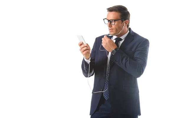 Serious businessman in eyeglasses talking on smartphone in earphones isolated on white background — Stock Photo