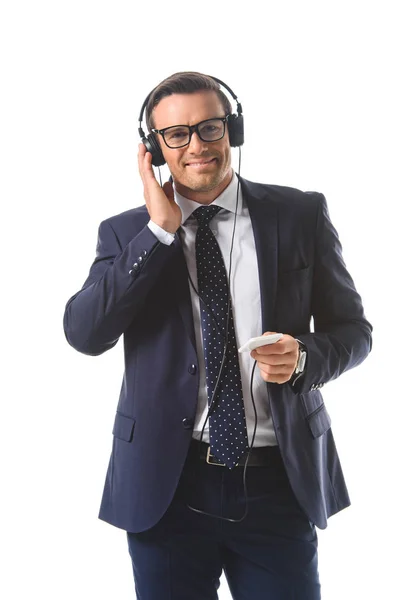 Lächelnder Geschäftsmann mit Brille, der Musik in Kopfhörern hört, Smartphone isoliert auf weißem Hintergrund — Stockfoto